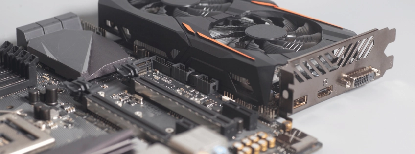 Zbliżenie na kartę graficzną zamontowaną na płycie głównej komputera – widoczne wentylatory GPU, slot PCIe oraz porty HDMI i DVI.