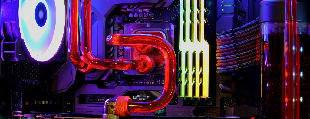Wydajny komputer gamingowy z customowym chłodzeniem cieczą – czerwone rurki, podświetlane RGB wentylatory i pamięć RAM, widoczne komponenty płyty głównej w nowoczesnej obudowie PC.
