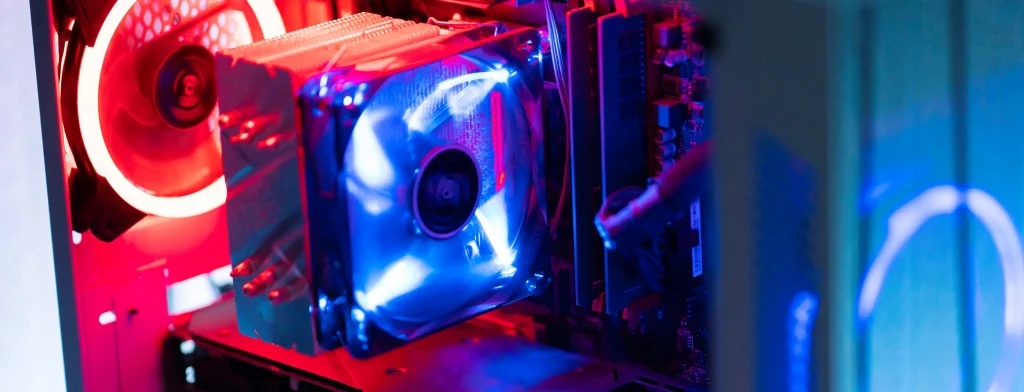 Wnętrze komputera stacjonarnego z chłodzeniem powietrznym CPU i podświetlanymi wentylatorami LED w kolorach czerwonym i niebieskim, ukazujące wydajny zestaw gamingowy.