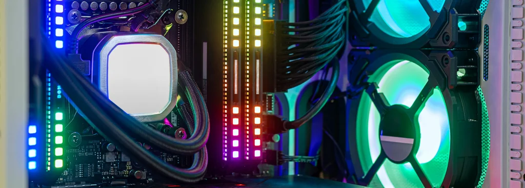 Nowoczesne wnętrze komputera PC z podświetleniem RGB – widoczna płyta główna, chłodzenie cieczą procesora, pamięć RAM z diodami LED oraz wentylatory obudowy.